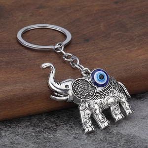 Detailed close-up of a vintage silver elephant keychain with blue evil eye bead and engraving