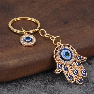 Detail of Hamsa Hand and Evil Eye gold keychain with blue crystals on stone