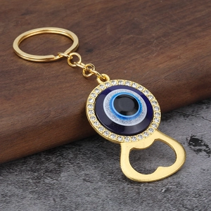 Golden Evil Eye bottle opener keychain with sparkling rhinestones on wood and stone