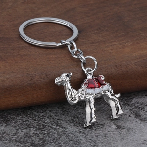 Detailed macro view of decorative silver metal camel keychain with red enamel saddle