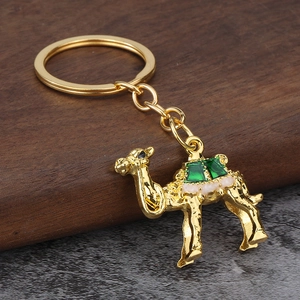 Exquisite golden camel keychain with green gemstone details and polished metal surface