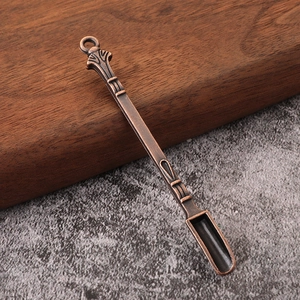 Detail shot of vintage bronze metal snuff spoon with embossed handle on stone surface