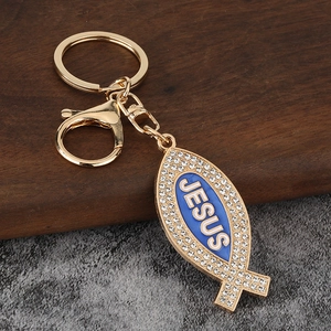 Close-up of golden metal Jesus fish keychain with white rhinestones and blue enamel inlay