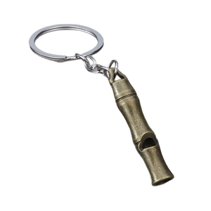Bamboo shaped vintage brass survival whistle with stainless steel keyring on white background