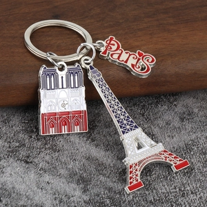 Paris souvenir keychain with Eiffel Tower and Notre Dame metal charms on wood background