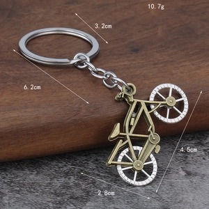 Vintage bronze bicycle keychain with silver wheels on a textured wooden background
