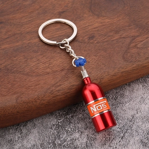 Macro detail of a red mini NOS nitrous oxide bottle keychain on a wooden surface