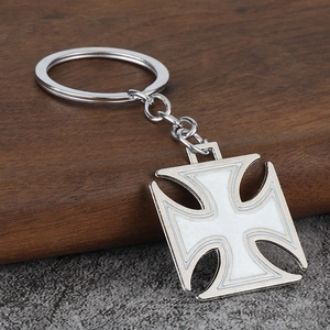 Detail of silver Iron Cross keychain with white enamel inlay on a rustic wood background