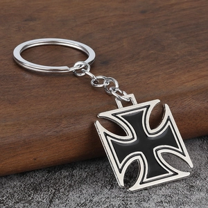 Macro detail of Iron Cross keychain with black enamel finish on vintage wood and stone