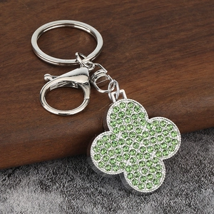 Porte-clés trèfle à quatre feuilles en argent avec cristaux verts sur fond de pierre