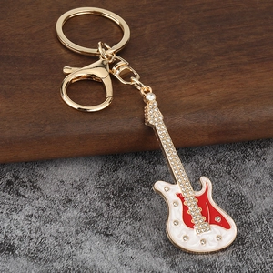 Détail du porte-clés guitare électrique dorée avec strass brillants et émail rouge élégant