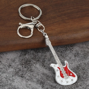 Détail macro du porte-clés guitare rouge avec strass et fermoir mousqueton en métal