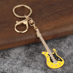 Détail d'un porte-clés guitare électrique avec émail jaune et strass brillants sur métal doré