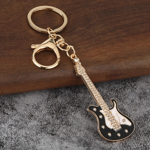 Détail d'un porte-clés guitare en alliage doré avec strass brillants et décor en émail
