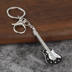 Détail d'un porte-clés mini guitare électrique avec strass brillants et fermoir mousqueton