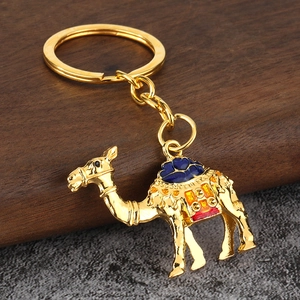 Détail d'un porte-clés chameau doré avec motifs en émail sur surface en bois sombre