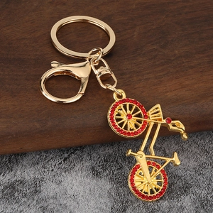 Detail of golden bicycle keychain with red rhinestones and lobster clasp on wood background
