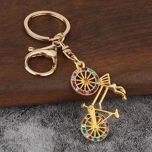 Detailed view of a golden bicycle keychain with colorful rhinestones on a wooden surface