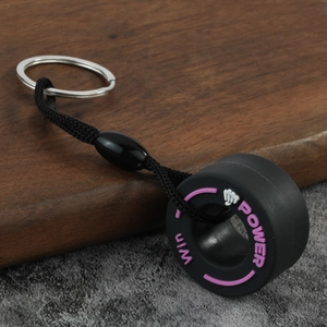 Detail of black silicone tire keychain with pink Win and Power text on a woven nylon strap