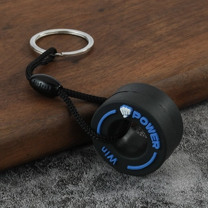 Close-up of PVC tire keychain with braided strap and blue POWER text on a wooden surface