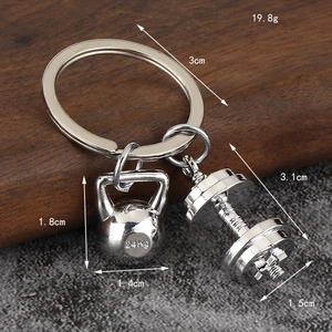 Silver metal fitness keychain with dumbbell and 24KG kettlebell pendants on wooden surface