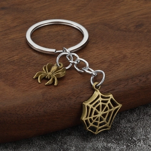 Bronze spider and web keychain accessories on rustic wood background for Halloween style