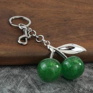 Detail of glitter green resin cherry keychain with silver leaves and lobster clasp