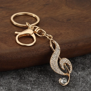 Golden musical treble clef keychain with sparkling rhinestones on textured background