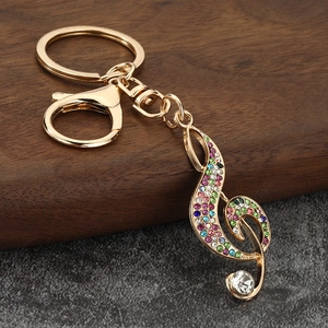 Close-up of music note keychain with colorful rhinestones on a textured stone surface