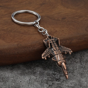 Vintage copper fighter jet metal keychain with detailed body on a wood and stone background