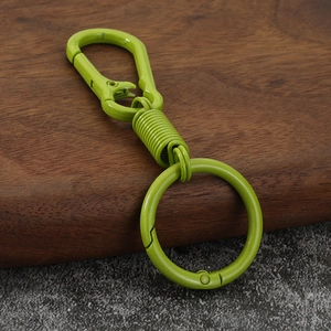 Detail of green zinc alloy carabiner keychain with spring loaded ring on stone surface
