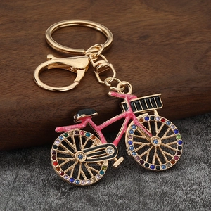 Detailed view of pink bicycle keychain with colorful rhinestones on a dark wood block