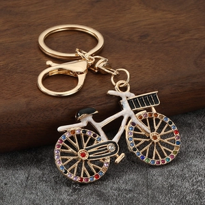 Detail shot of golden bicycle keychain with rhinestones and white enamel finish