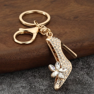 Sparkling gold high heel keychain with white rhinestones and crystal flower on wood