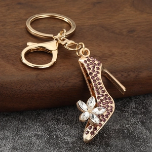 Detailed view of a gold high heel keychain with purple rhinestones and crystal flower detail