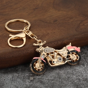 Detailed close-up of golden motorcycle keychain with sparkling rhinestones and pink enamel
