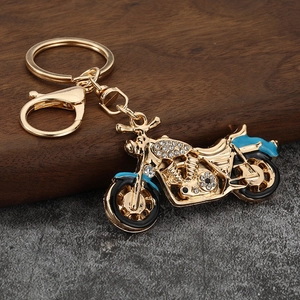 Detailed close-up of a rhinestone studded motorcycle keychain with blue enamel accents