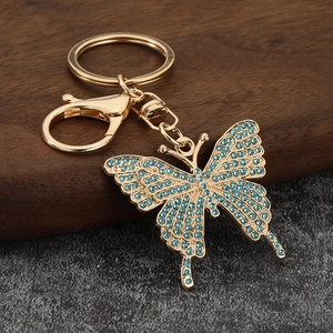 Detail of golden butterfly keychain with inlaid sky blue rhinestones on wooden surface