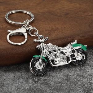 Macro shot of silver motorcycle keychain featuring sparkling rhinestones and green enamel details