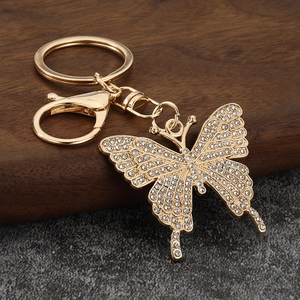 Close-up of golden butterfly keychain with shimmering crystals on a wooden surface