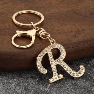 Detailed close-up of golden letter R keychain featuring sparkling inlaid rhinestones