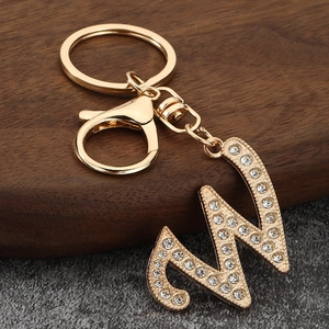 Detailed close-up of golden metal letter M keychain with sparkling rhinestone inlay