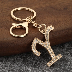 Macro detail of a gold letter Y keychain with sparkling white rhinestones on dark wood