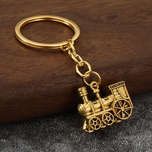 Detailed close-up of a vintage golden steam locomotive keychain on a textured surface