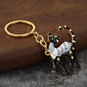 Fashionable enamel cat keychain with tricolor pattern and golden metal ring on dark surface