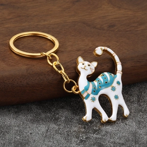 Chic enamel cat keychain with golden metal finish and floral pattern on solid wood background
