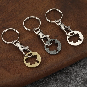 Three zinc alloy cart token keychains in bronze, black and silver on wood background