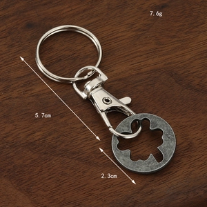 Zinc alloy trolley token keychain with a cutout flower design on a wooden background