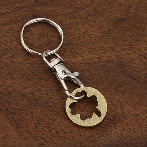 Zinc alloy trolley coin keychain with a vintage clover pattern on a wooden background