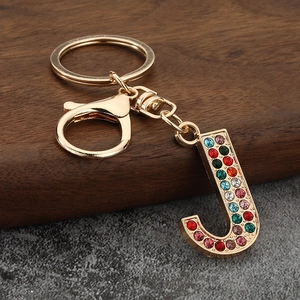 Close-up of letter J keychain featuring colorful rhinestones on a gold metal frame
